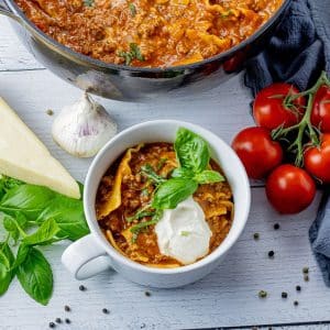 white bowl filled with lasagna soup topped with ricotta cheese and basil