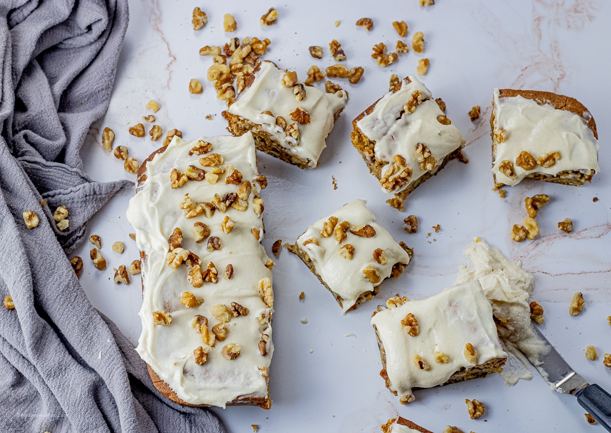 maple cake topped with white frosting and chopped walnuts sliced into pieces