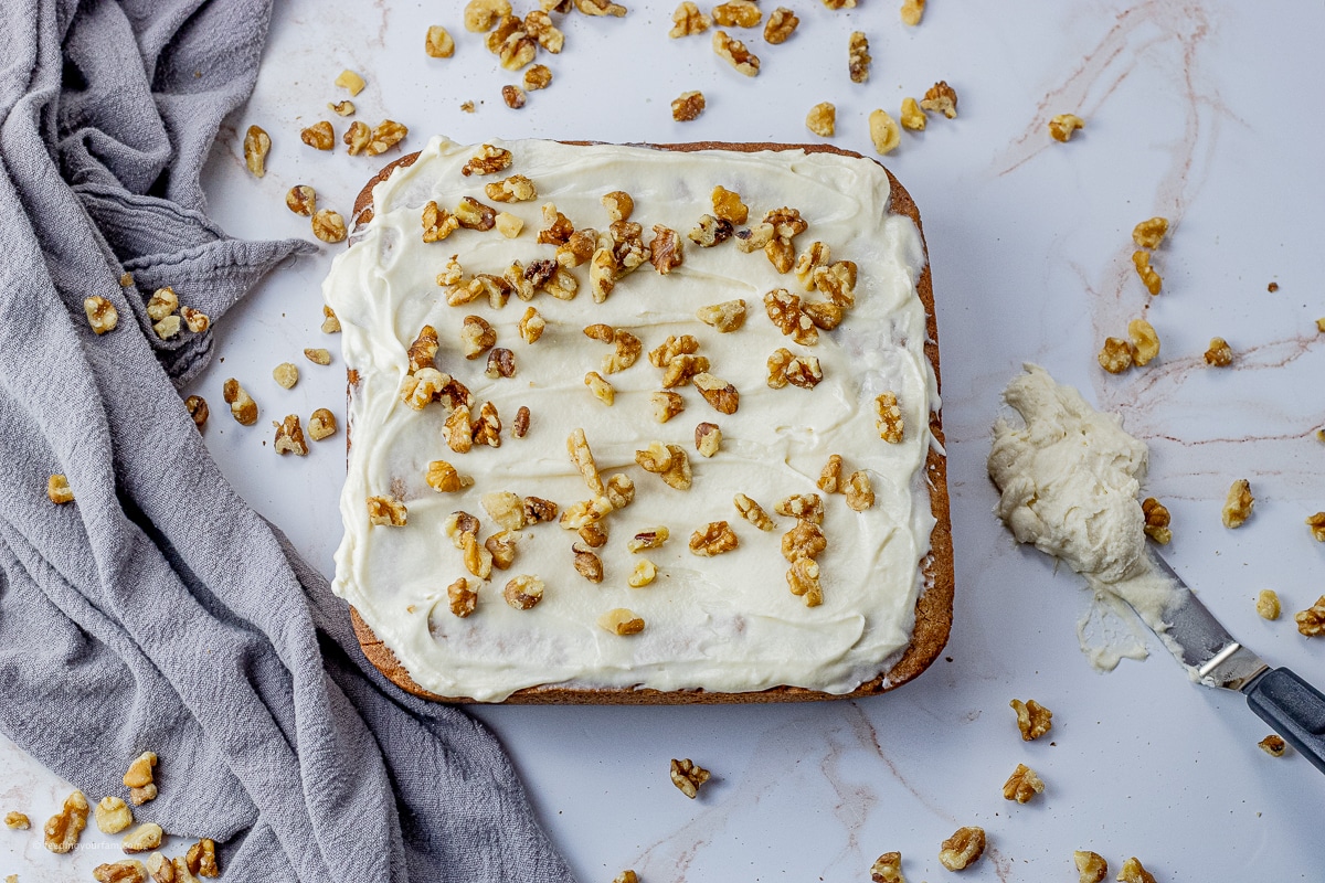 square cake topped with vanilla frosting and chopped walnuts