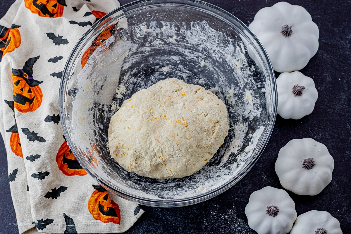 cheesy biscuit dough ball in a glass mixing bowl