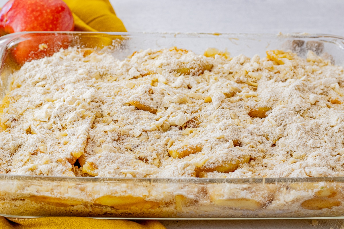 uncooked apple pie bars with a buttery topping and apples in the center