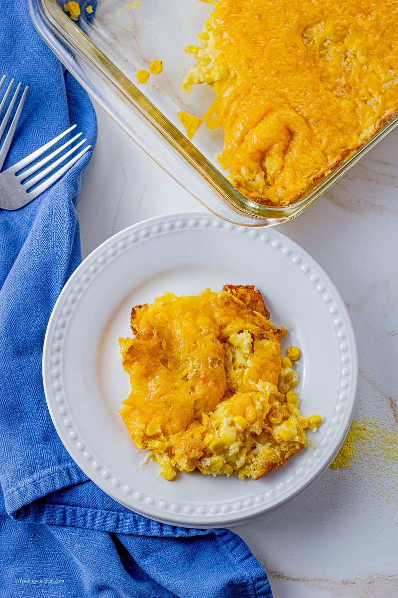 scoop of cornbread casserole with cheese on a white, round plate