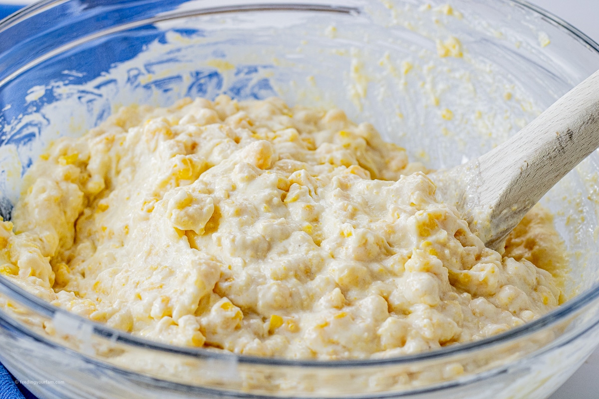 creamed corn and corn kernels mixed with sour cream and corn muffin mix to make a corn casserole in a mixing bowl