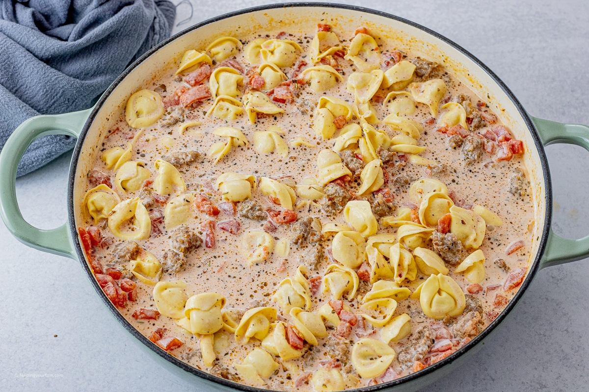 tortellini in a big skillet cooking in a cream and tomato sauce