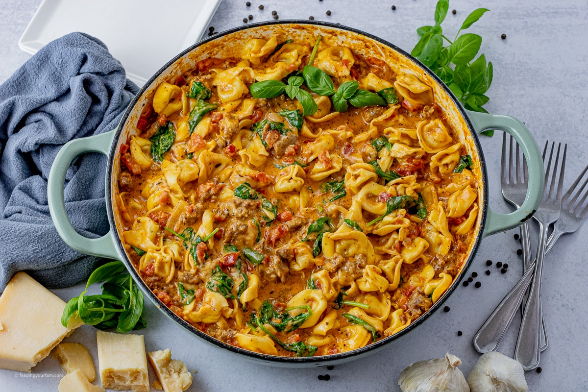 big skillet of tortellini with sausage and spinach in a tomato cream sauce