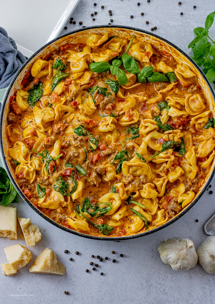 big pan of tortellini in a creamy, tomato sausage sauce