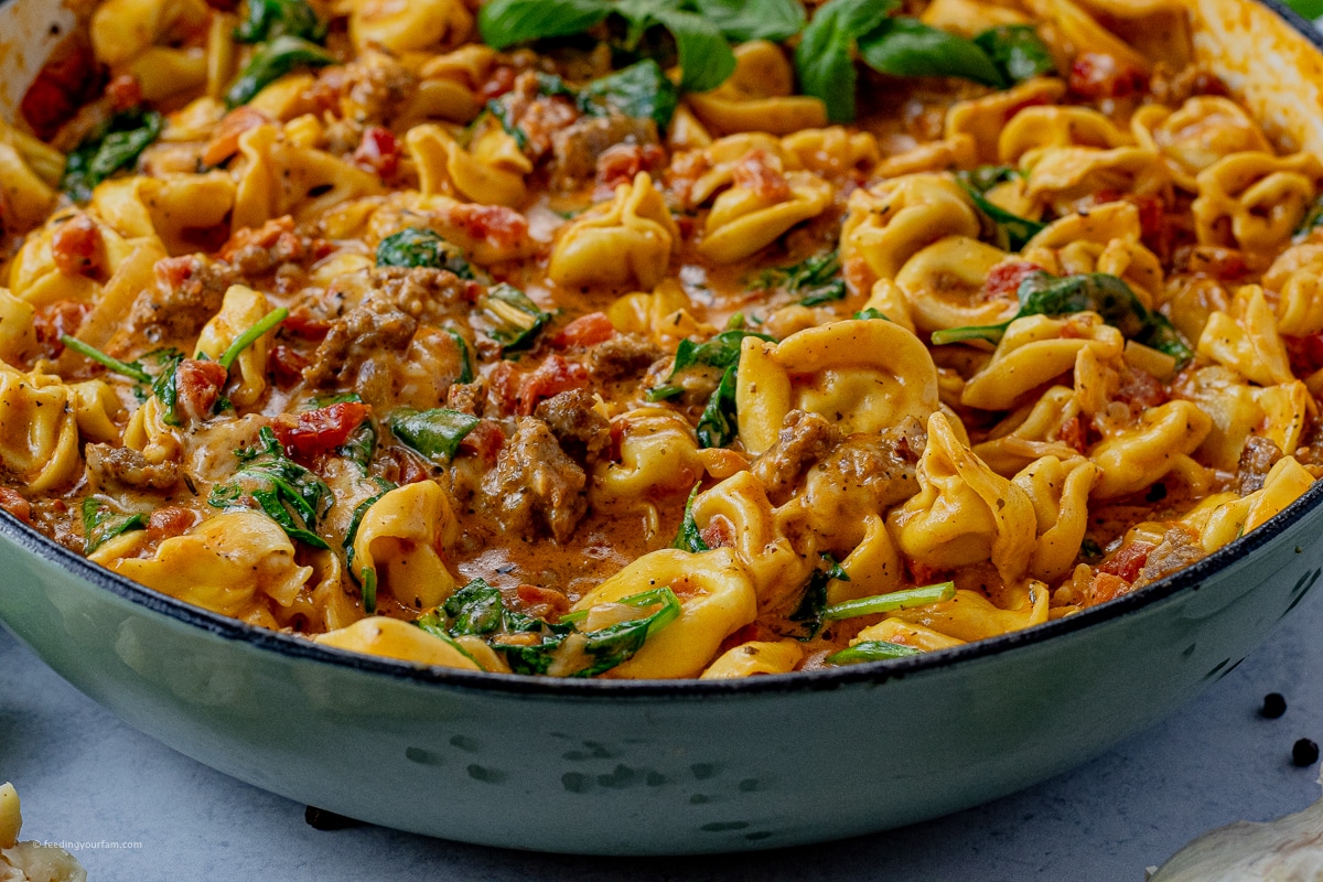 tortellini in a skillet cooked in a creamy tomato cream sauce