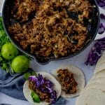 pan with pulled pork and two tacos next to it