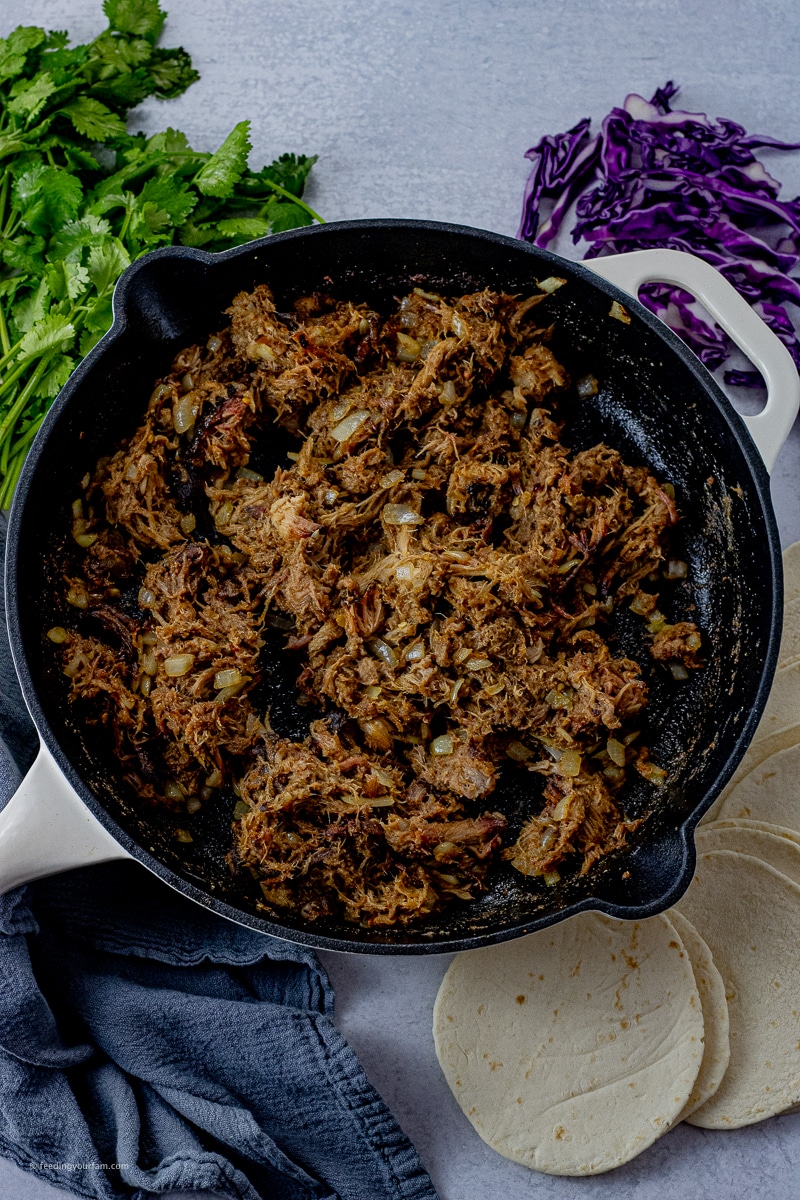 pulled pork in a cast iron pan with onions and taco seasoning