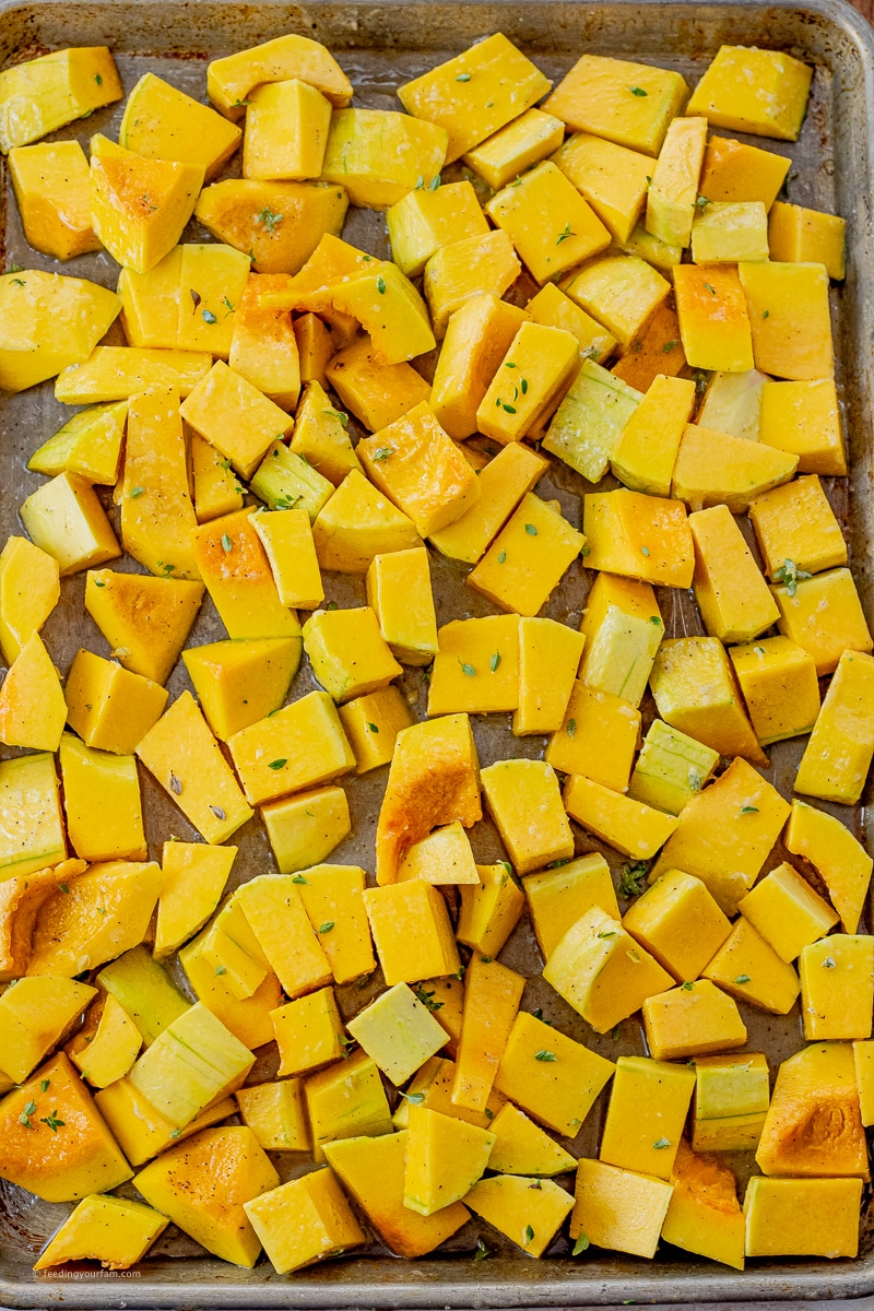 pieces of butternut squash on a baking sheet that has been seasoned with salt, pepper and thyme
