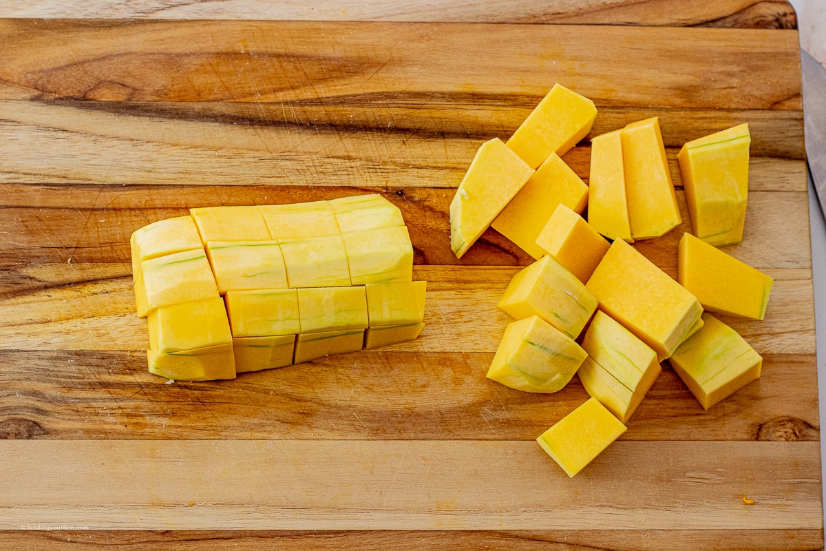 butternut squash sliced into pieces on a wooden cutting board
