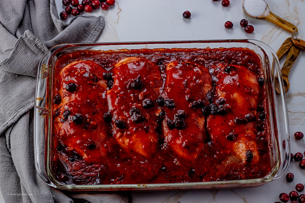 glass baking dish with cooked chicken in a cranberry sauce