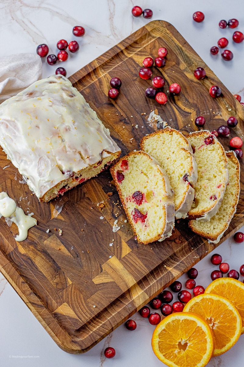 sliced orange cranberry bread on a wooden cutting board