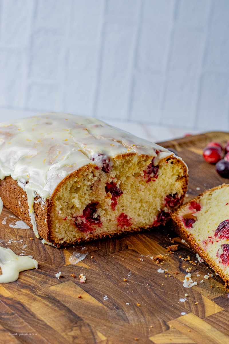 sliced cranberry bread covered with an orange glaze on a wooden cutting board