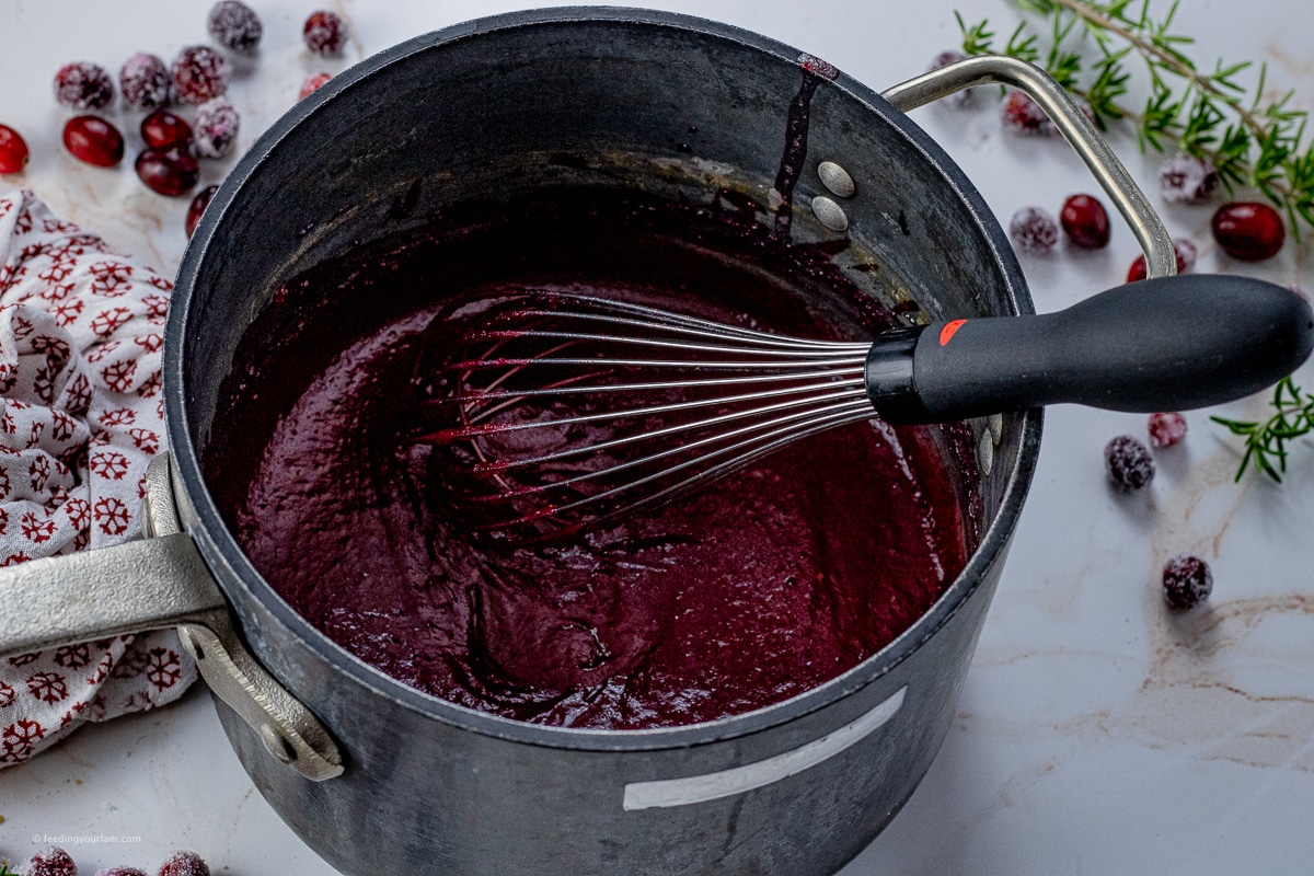 cooked cranberries with a whisk in a large saucepan