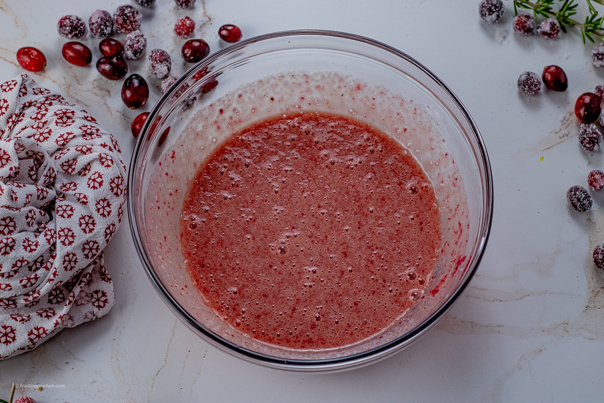 whisked eggs mixed with cooked cranberries in a glass mixing bowl