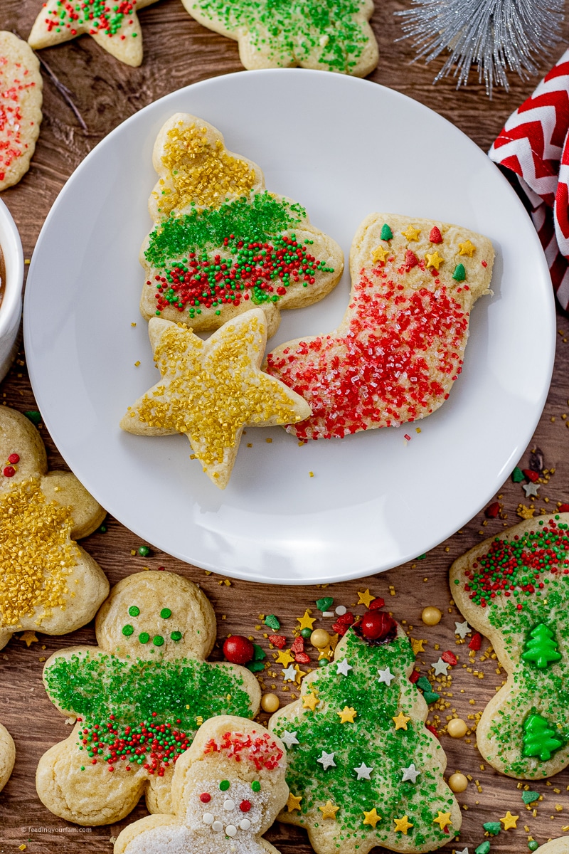 cookies cut out in the shape of a star, stocking and tree covered in sprinkles