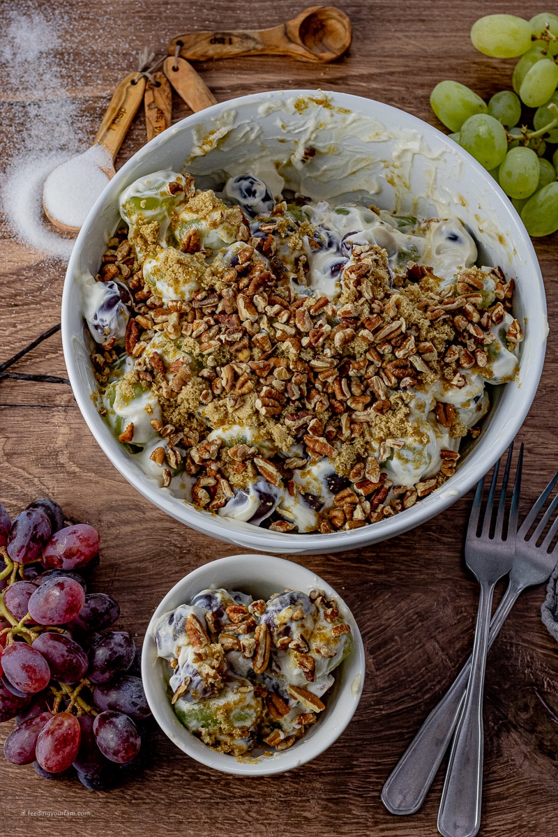 salad made with grapes in a cream cheese dressing topped with brown sugar and pecans
