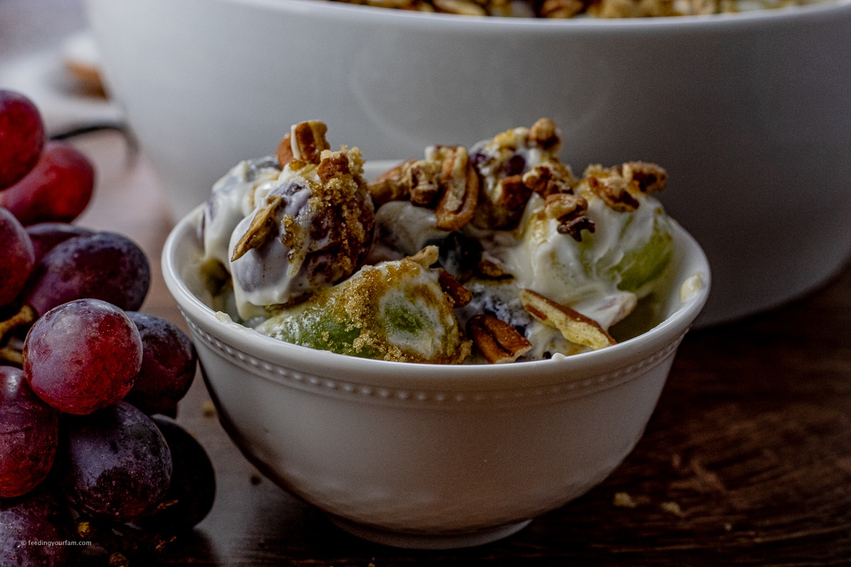 small, white bowl filled with red and green grape salad with brown sugar and pecans