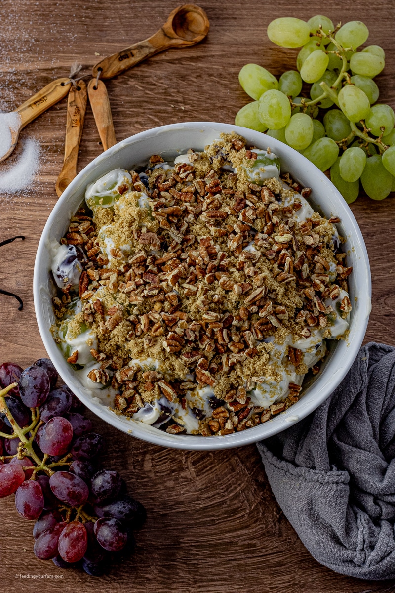 This Grape Salad Recipe is a simple and quick side dish that is loaded with red and green grapes in a creamy dressing covered in brown sugar and pecans. Perfect for potlucks and family get togethers!