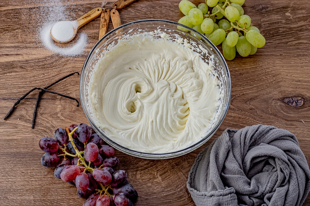cream cheese and sour cream dressing for grape salad mixed in a glass mixing bowl
