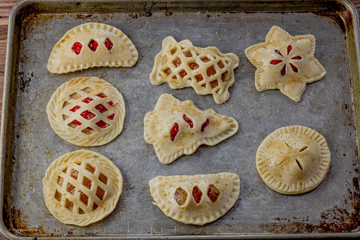 small hand pies shaped in different shapes on a baking sheet