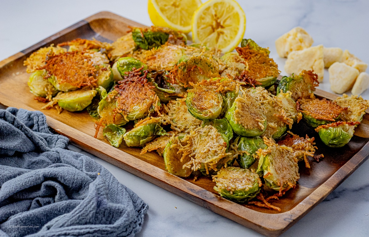 brussels sprouts cut in half and cooked in parmesan cheese on a wooden platter