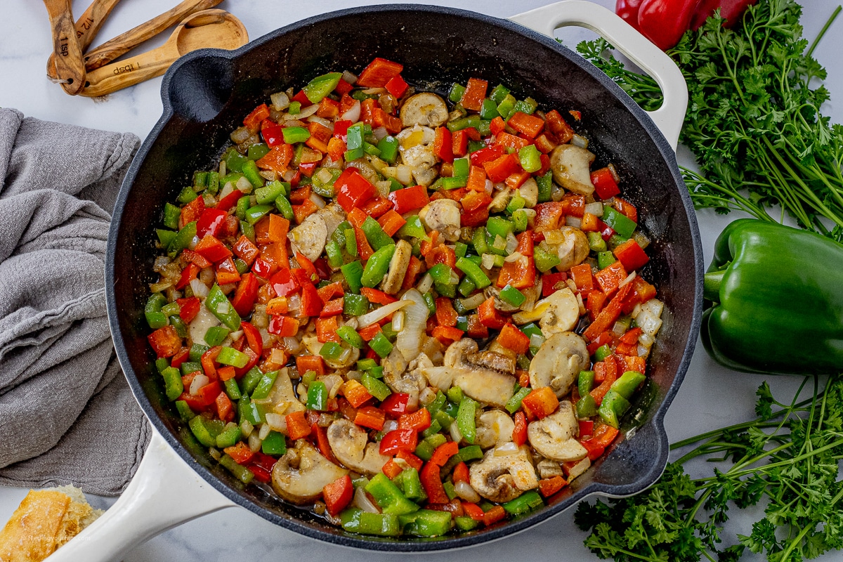 green, red peppers with mushrooms and onions cooked in a cast iron pan