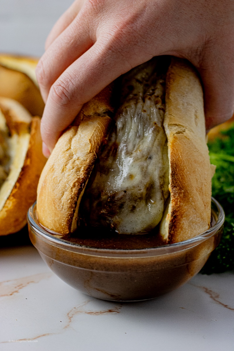 dipping a shredded beef sandwich into au jus