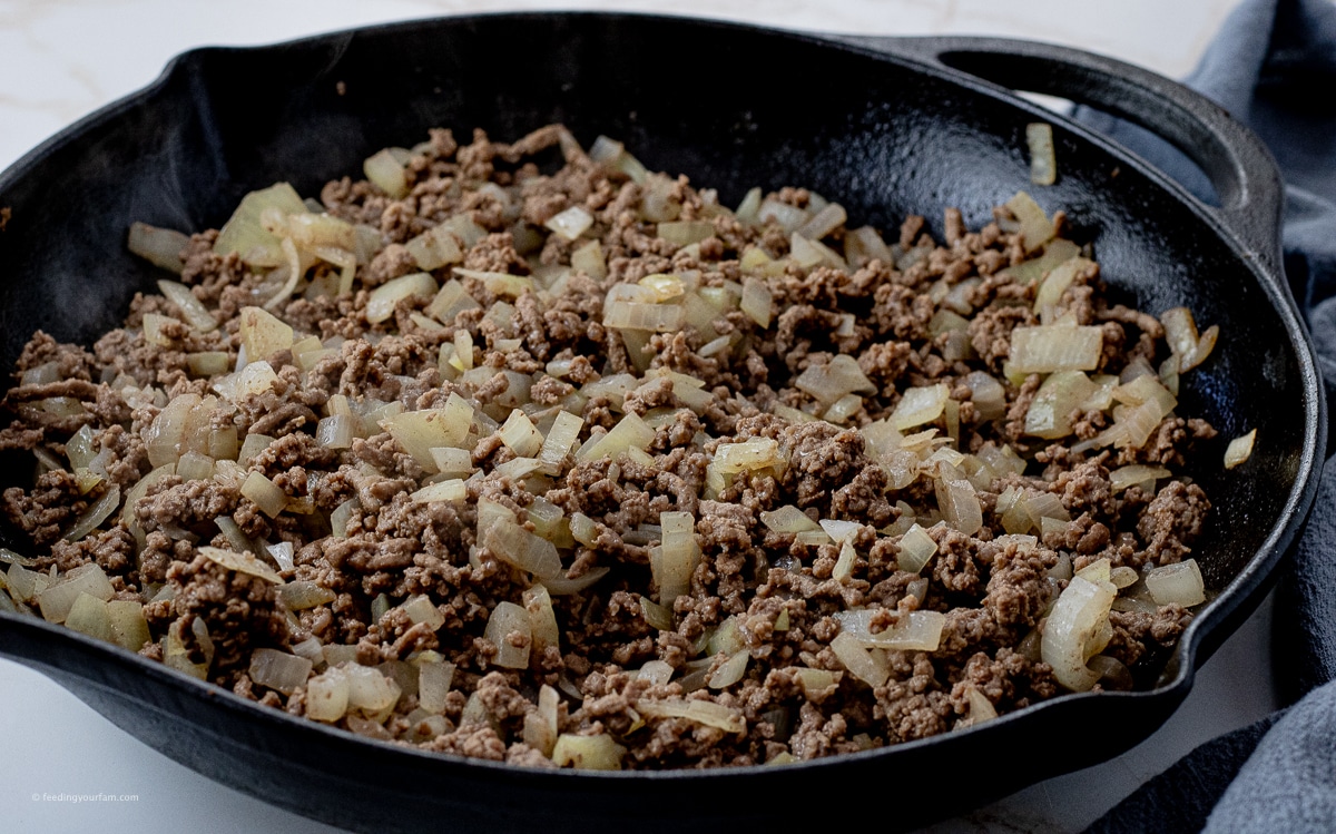 browned ground beef and onions in a cast iron pan