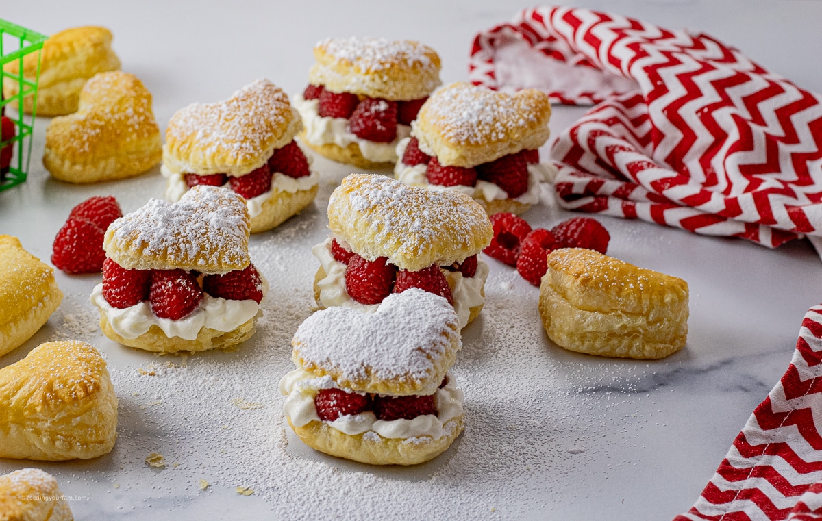 small heat shaped puff pastries filled with whipped cream and raspberries