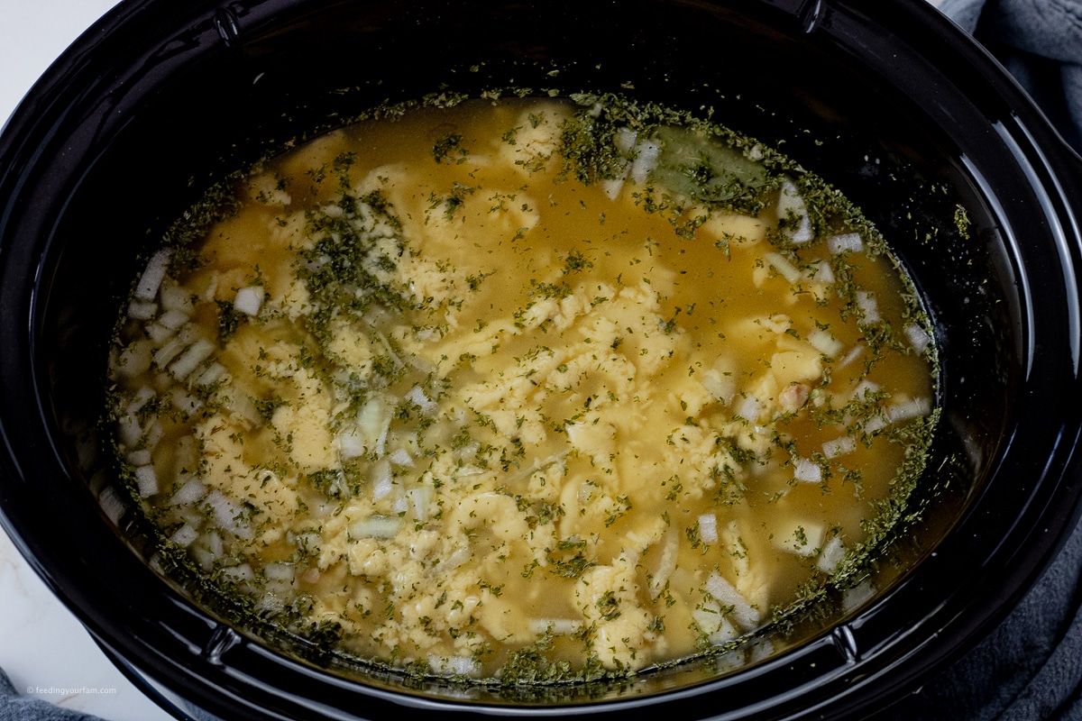 crockpot full of chicken breasts, cream of chicken soup, chicken broth and onions 