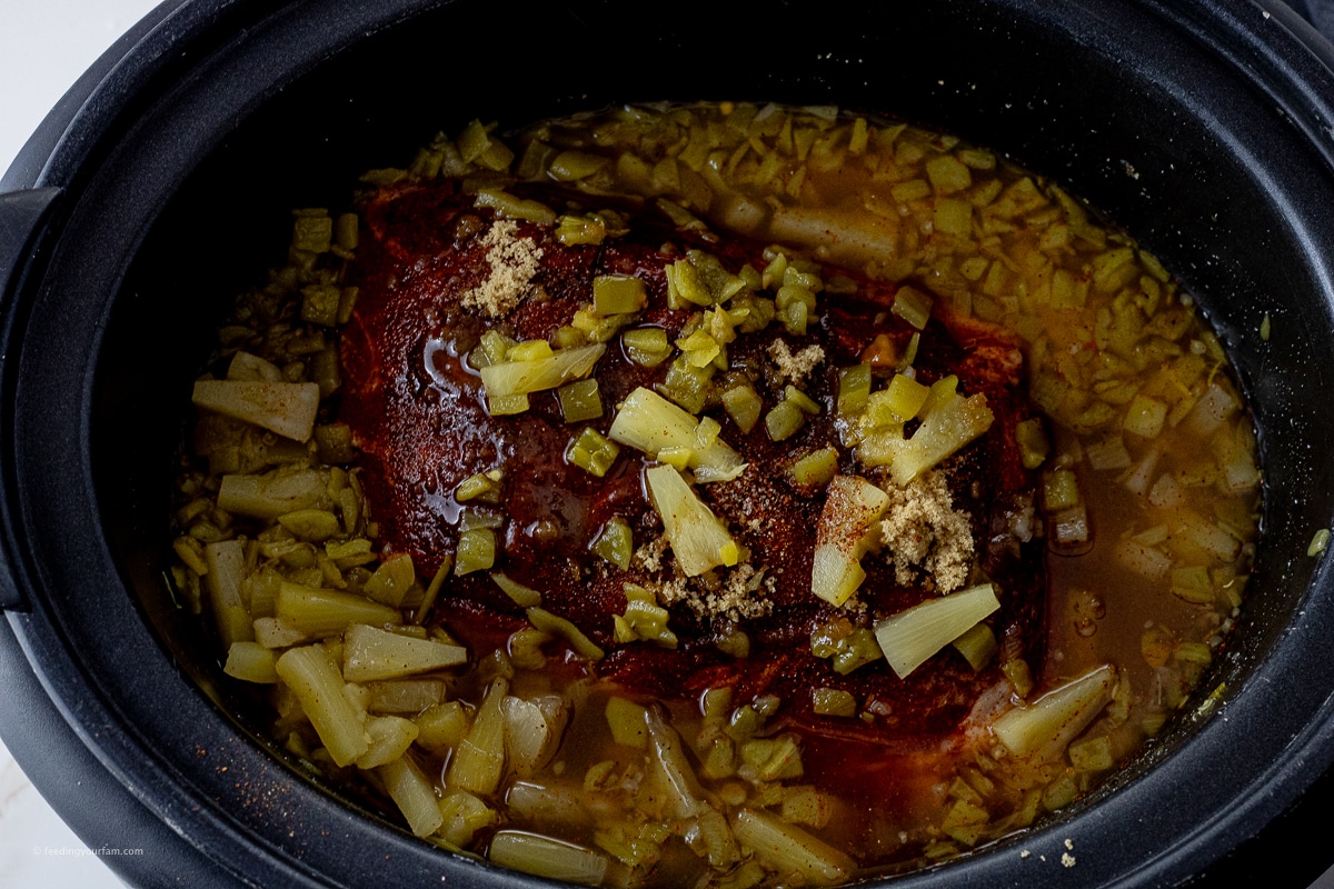 pork roast covered with pineapple tidbits, brown sugar and chicken broth in a slow cooker pot