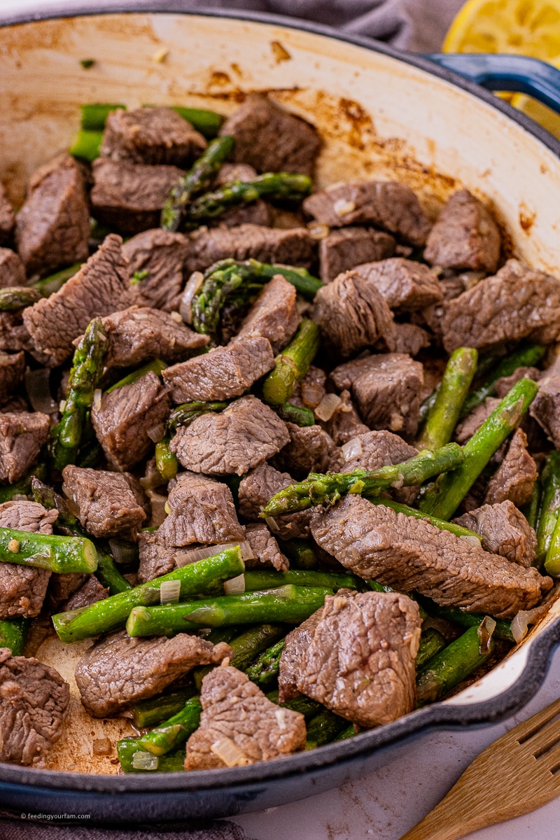 steak bites in garlic butter with asparagus in a large cast iron pan