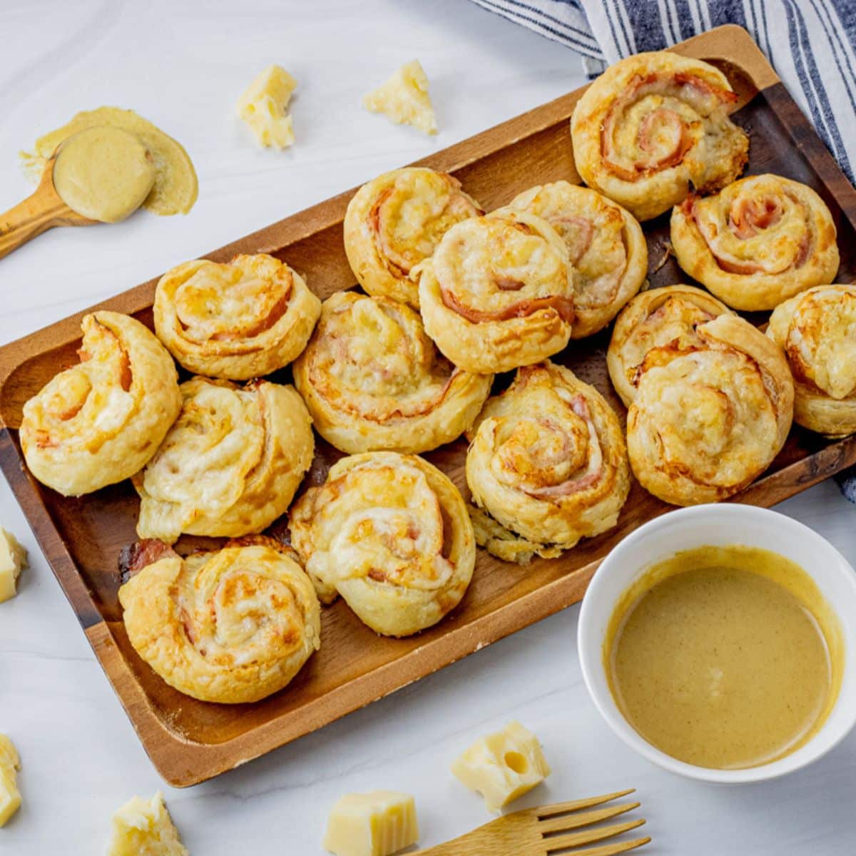 rolled ham and cheese pinwheels on a wooden platter