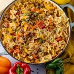 peppers, bowtie pasta and sausage in a round pan