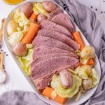 sliced corned beef sliced on a platter with potatoes, carrots and cabbage