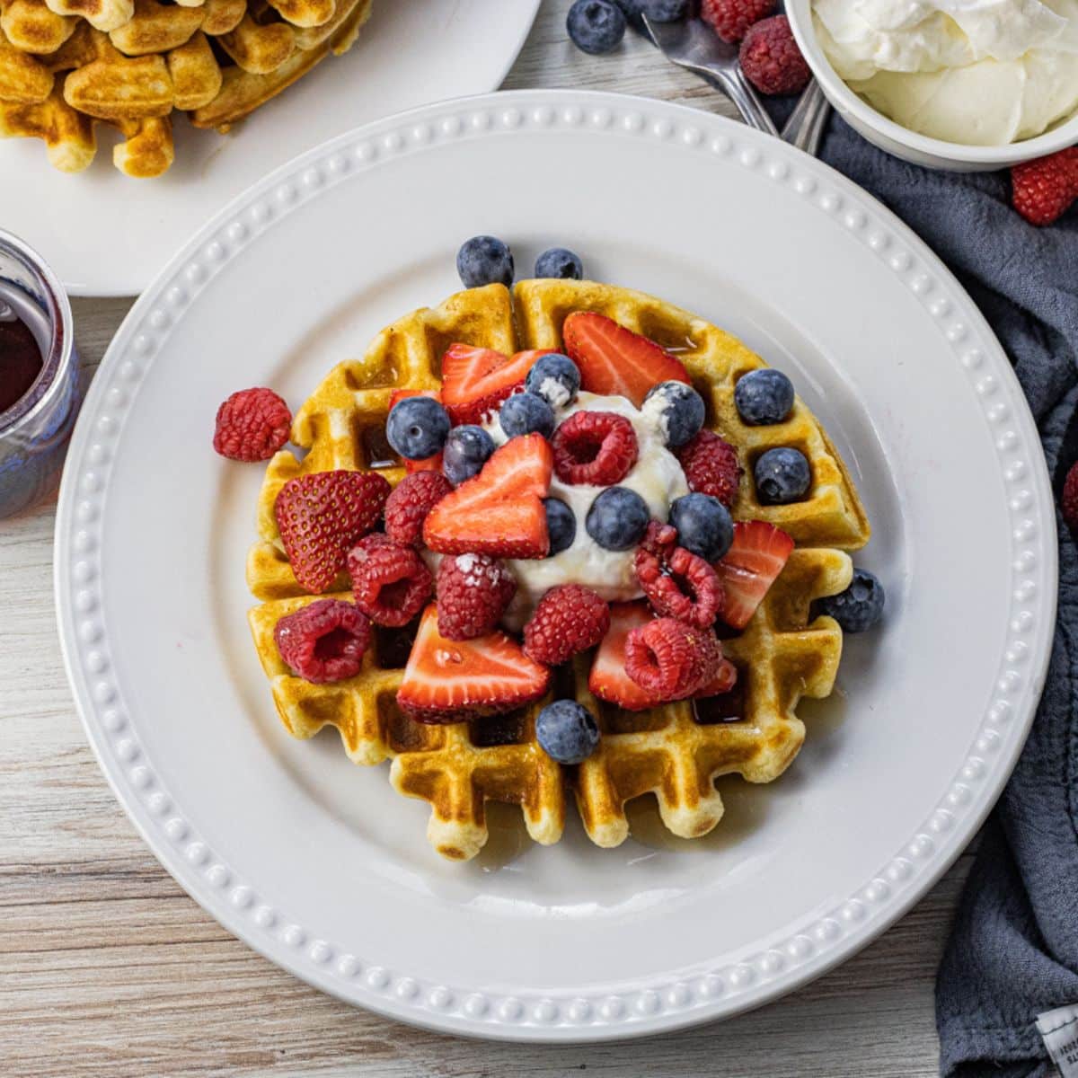 round waffle topped with fresh fruit and whipped cream