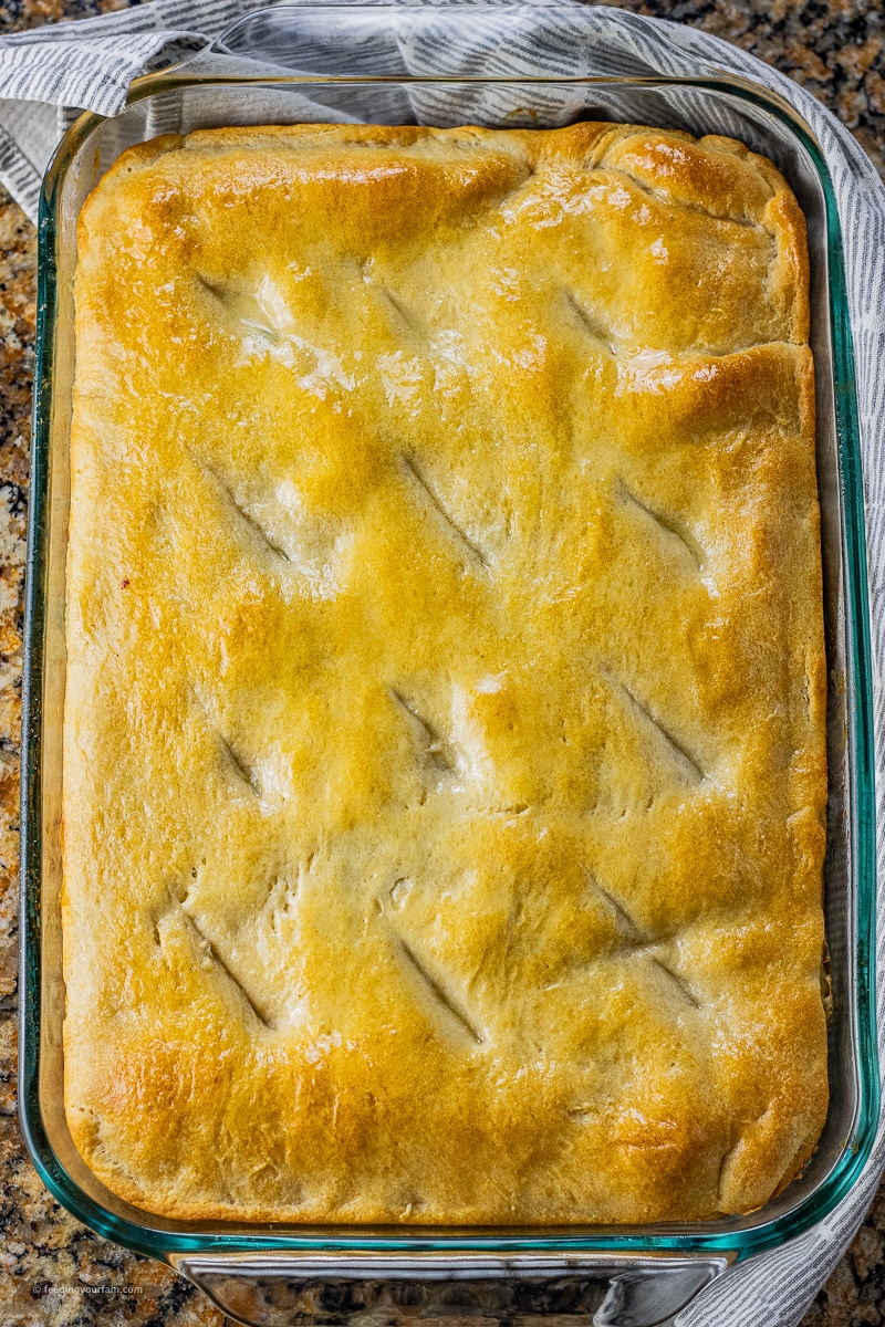browned crescent roll dough on top of chicken pot pie filling in a rectangle pan