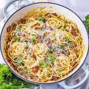 swirls of pasta with bacon and parmesan in a large round pan
