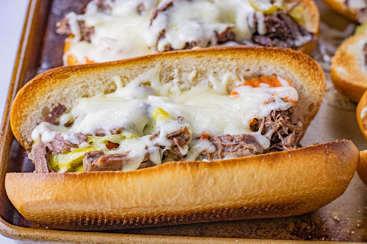 sliced hoagie bun topped with shredded beef, pepperoncini and melted cheese