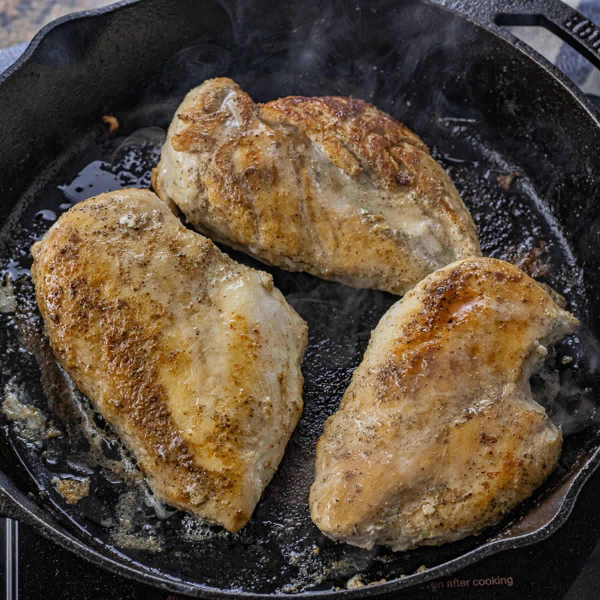 three chicken breasts cooked in a black cast iron pan