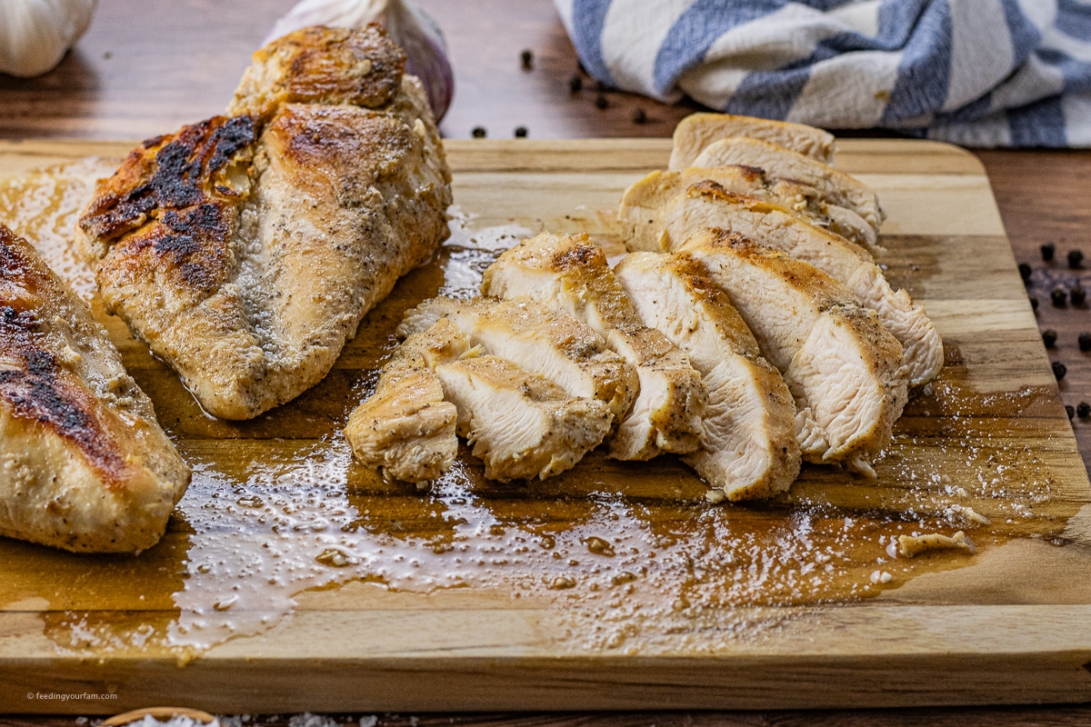 cooked chicken on a wooden cutting board, one is sliced