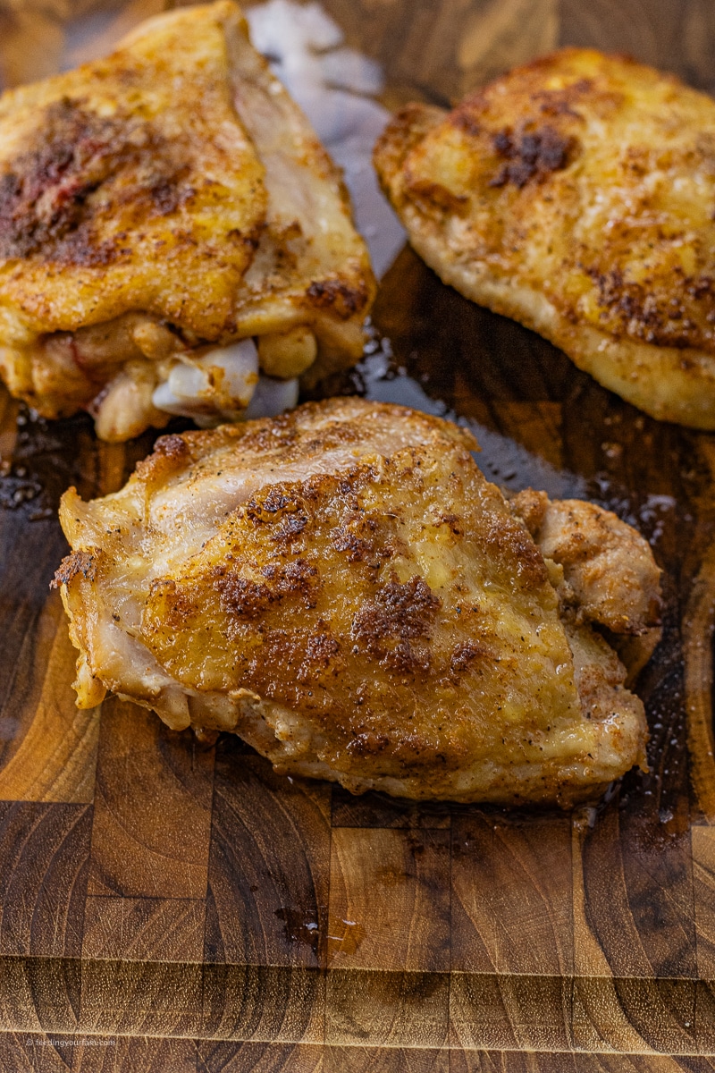 cooked chicken thigh on a wooden cutting board