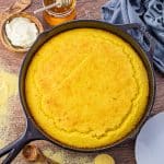 large cast iron skillet cornbread on a wooden background