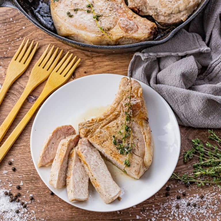 bone in pork chop sliced and on a white round plate