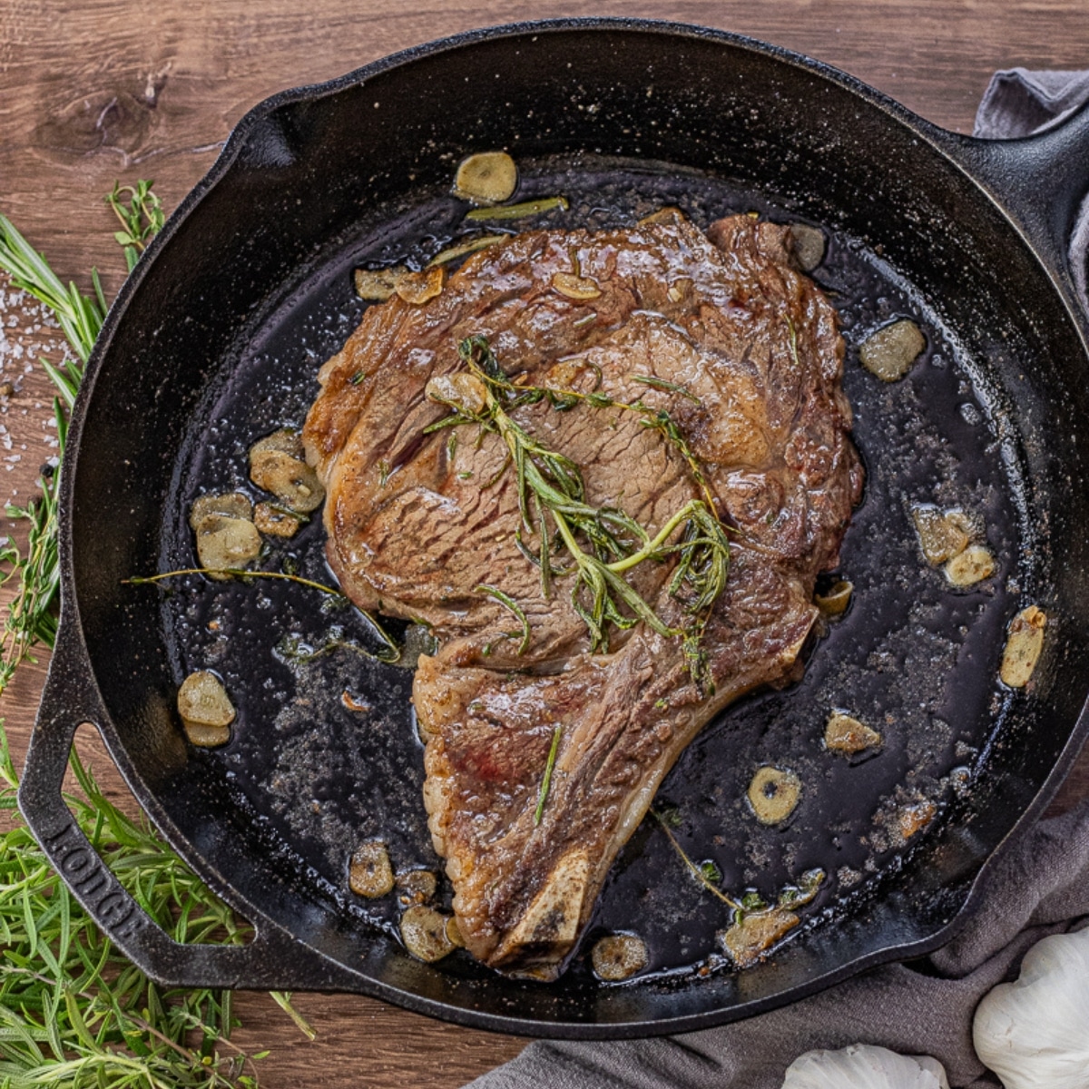 ribeye cooked in a cast iron skillet topped with rosemary and thyme