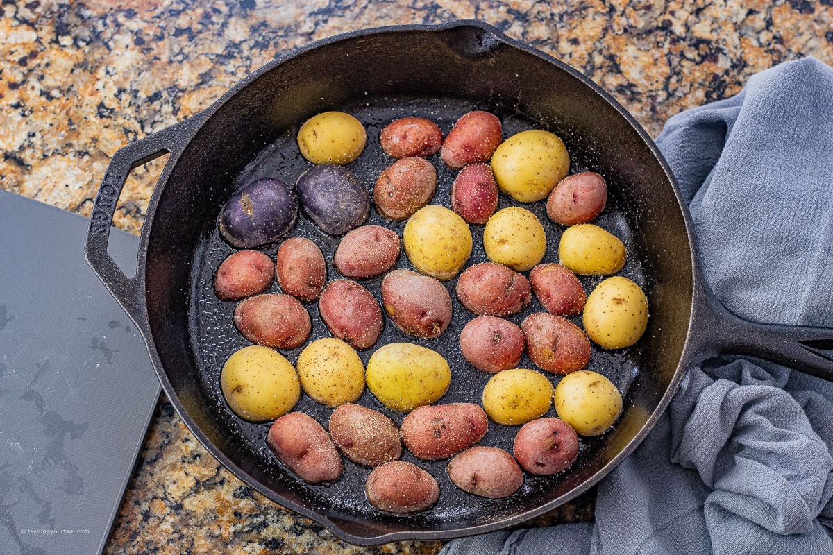 small potatoes cut in half and cooking in a cast iron skillet