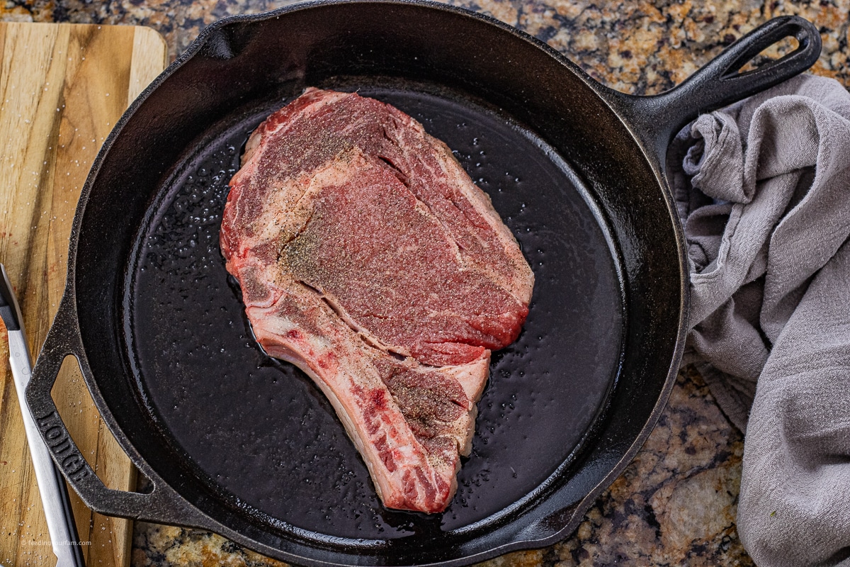 ribeye steak cooking in a cast iron pan