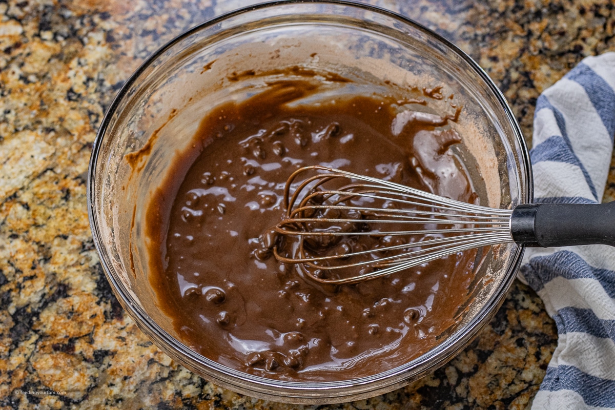 mixing bowl with brownie batter with chocolate chips in it and a whisk